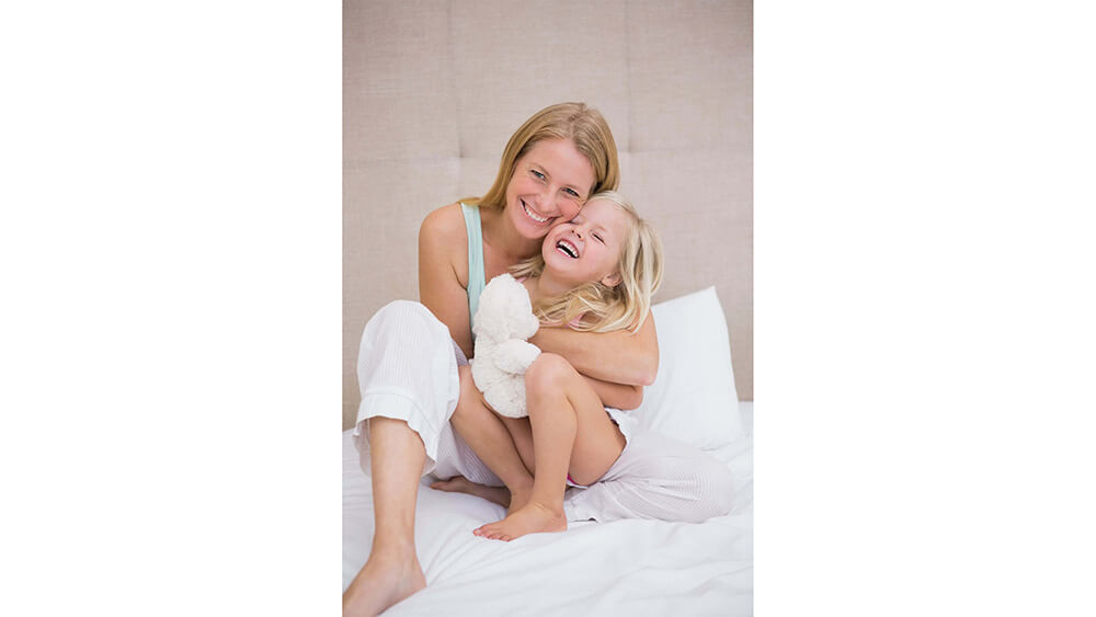 Woman holding her child on a bed