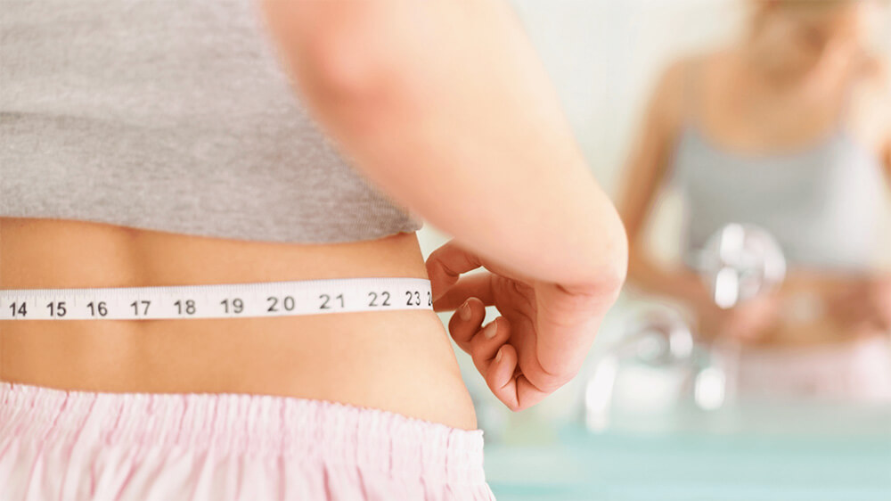 Woman measuring her waist in the mirror